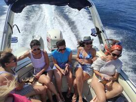A lively group of friends enjoys a fun day on the water, sharing drinks and laughter aboard a speedboat, perfect for summer adventures.