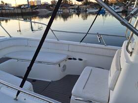 Interior view of a boat's seating area, showcasing comfortable white upholstery and a spacious layout, perfect for relaxing while on the water.