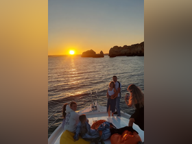 A joyful family enjoys a sunset cruise on a boat, capturing memories against a stunning backdrop of golden hues and rocky formations.