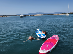 Two children enjoy a fun day of paddleboarding and swimming in clear waters, showcasing the excitement of summer water activities.
