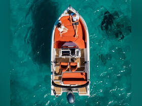 A couple relaxes on a stylish boat with vibrant orange seating, surrounded by stunning turquoise waters — perfect for a romantic getaway or day on the water.