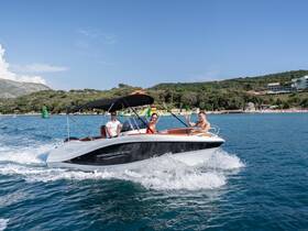 A group enjoys a thrilling ride on a Barracuda 545 boat, showcasing the excitement of on-water activities in a picturesque setting.