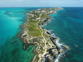 A stunning aerial view of a picturesque coastline with turquoise waters and lush greenery, perfect for showcasing the beauty of island destinations.