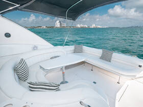 A stylish interior view of a boat's lounge area featuring comfortable seating and a table, perfect for relaxing while enjoying the scenic waterfront.