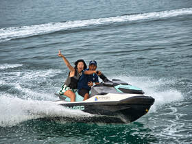 A joyful couple rides a jet ski, showcasing the thrill of water sports and adventure on the open sea.