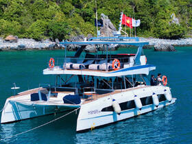 A stunning catamaran anchored in clear waters, showcasing its sleek design and vibrant flags, perfect for luxury charters and island adventures.