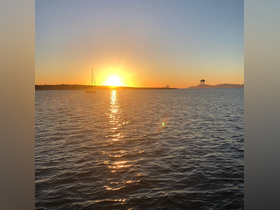 A serene sunset view featuring a sailboat silhouetted against the vibrant horizon, perfect for capturing the tranquility of evening on the water.