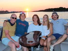 A family enjoys a picturesque sunset on a boat, creating lasting memories together — perfect for family outings and celebrations on the water.