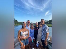 A cheerful group of friends poses together on a boat, enjoying a beautiful day on the water — perfect for summer celebrations and memorable outings.