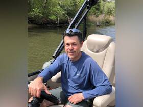 A man enjoys a leisurely moment at the helm of a boat, surrounded by lush greenery — perfect for a day of exploration on the water.