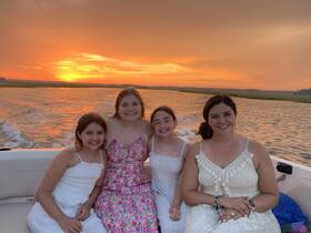 A joyful family poses together on a boat at sunset, capturing a beautiful moment of togetherness and celebration on the water.