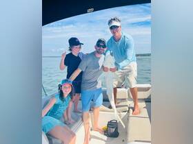 A joyful family poses on a boat, showcasing their catch of the day — a shark, making for an unforgettable fishing adventure.