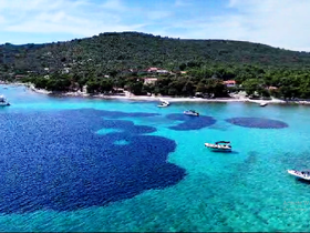 A stunning aerial view of a picturesque coastline with crystal-clear waters and boats anchored, perfect for island hopping adventures.
