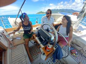 A lively group enjoys sailing on a beautiful day, showcasing smiles and camaraderie aboard the boat.