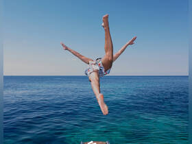 A person joyfully jumps into the crystal-clear ocean, capturing the essence of fun water activities during a boating adventure.