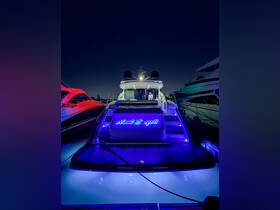 A stunning view of the yacht 'Naut Boys II' illuminated at night, showcasing its sleek design and vibrant lighting while docked at Lighthouse Point.