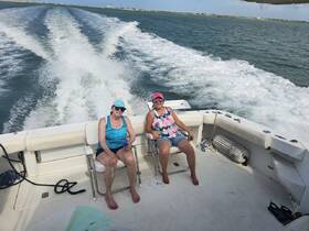 Two friends enjoy a relaxing day on the water, soaking up the sun aboard a boat — perfect for a fun day out with friends.