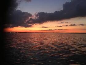 A stunning sunset over calm waters, showcasing vibrant colors reflecting on the surface — perfect for serene evening boat rides.