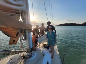 A joyful group celebrates aboard a sailboat during sunset, capturing the essence of a perfect sailing adventure.