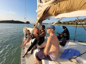 A group of friends relaxes on the deck of a sailboat, enjoying the serene waters and beautiful sunset — perfect for a memorable sailing experience.