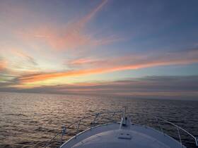 A stunning sunset view from the bow of a yacht, showcasing the serene ocean and vibrant sky — perfect for evening cruises.