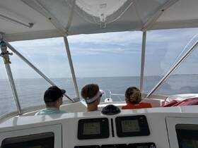 Three guests enjoy a scenic view from the helm of a boat, capturing the essence of a relaxing day on the water.