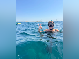 A snorkeler gives a cheerful sign while enjoying the clear waters, capturing the essence of adventure and fun in the sun.