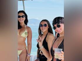 A lively group of friends enjoys a sunny day on a boat, showcasing fun and celebration in stylish swimwear — perfect for summer outings and beach parties.
