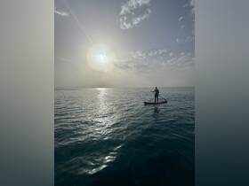 A paddleboarder enjoys a serene moment on the water during sunset, capturing the essence of adventure and tranquility on the open sea.