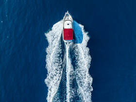 A stunning aerial view of a speedboat cruising through deep blue waters, showcasing its sleek design and dynamic movement.