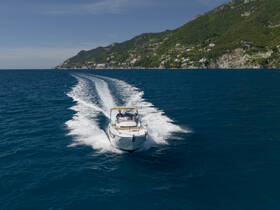 A couple enjoys a thrilling ride on a boat, cutting through the vibrant blue waters with stunning coastal scenery in the background — perfect for adventure seekers.
