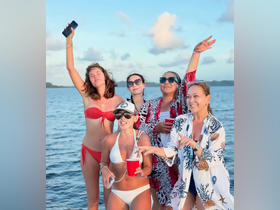 A lively group of friends celebrates on a boat, enjoying drinks and the beautiful ocean backdrop — perfect for summer parties and memorable outings.