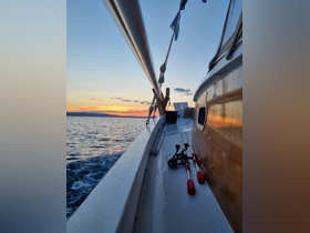 A serene sunset view from the deck of a boat, showcasing fishing gear and the tranquil waters, perfect for a relaxing day on the sea.