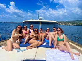 A lively group of friends enjoys a sunny day on a yacht, sipping cocktails and soaking up the sun — perfect for a fun getaway or celebration on the water.