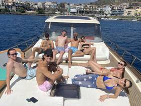 A lively group enjoys sunbathing and drinks on the deck of a yacht, capturing the essence of a perfect summer day on the water.