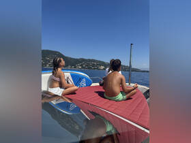 Two children enjoy a relaxing moment on the deck of a boat, surrounded by stunning water views — a perfect snapshot of summer fun on the water.