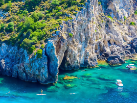 A stunning aerial view of a vibrant coastline with paddleboarders and swimmers enjoying the crystal-clear waters — a perfect scene for adventure seekers and nature lovers.