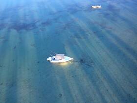 Aerial view of a boat anchored in clear turquoise waters, showcasing the serene beauty of the marine environment.