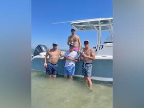 A group of friends enjoys a fun day in the water, celebrating with drinks next to their boat — perfect for summer outings and beach parties.