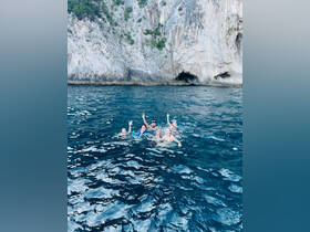 A lively group enjoys a refreshing swim in the open water, surrounded by stunning coastal cliffs — perfect for summer adventures and memorable outings.
