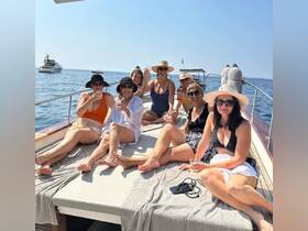 A lively group of friends enjoys cocktails on the deck of a yacht under the sun, perfect for celebrations and summer outings on the water.