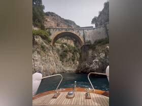A stunning view of a boat navigating through a rocky coastline with an impressive arch bridge overhead, showcasing the natural beauty of the area.