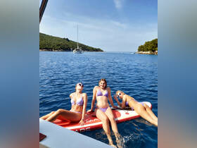 A fun group of friends enjoys paddleboarding in crystal-clear waters, soaking up the sun and creating unforgettable memories on their boating adventure.