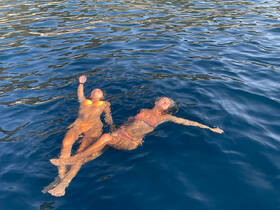 Two friends enjoy a refreshing swim in crystal-clear waters, soaking up the sun and embracing the ultimate summer vibe.