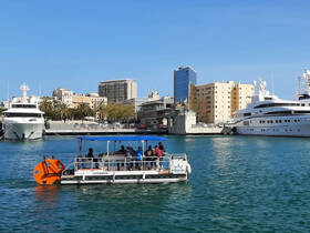 A lively group enjoys a boat ride in the harbor, surrounded by stunning city views and luxury yachts — perfect for sightseeing and exploring the waterfront.