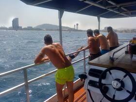 A group of friends leans over the railing of a boat, enjoying the ocean view and the warm sun — a perfect moment for relaxation and camaraderie on the water.