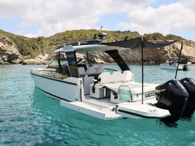 A sleek yacht named 'Dry Martini' anchored in crystal-clear waters, showcasing its elegant design against a stunning natural backdrop.