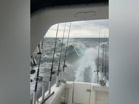 View from the helm of a fishing boat, showcasing fishing rods and the turbulent sea behind, perfect for deep-sea fishing adventures.