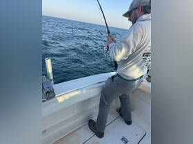 A fisherman reels in a catch while enjoying a day on the water — a perfect moment for fishing enthusiasts.