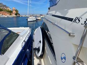 A close-up view of two yachts docked side by side in a marina, showcasing their sleek designs against a clear blue sky.